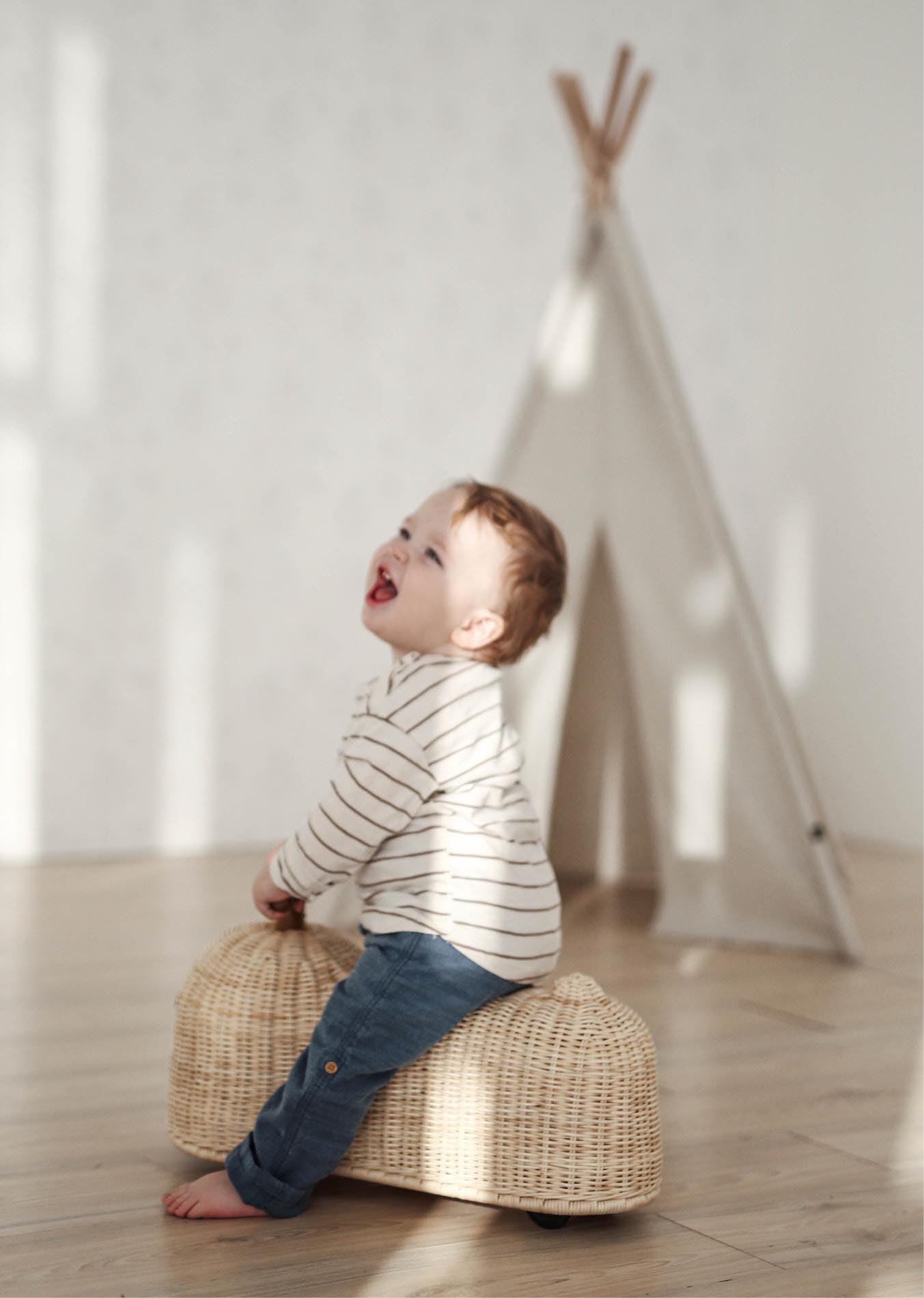 Child playing with Ride On Toy made of Rattan